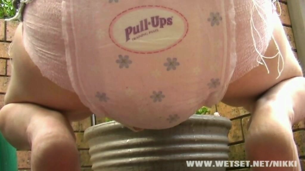 cute girl poos and wet her pampers while watering the garden